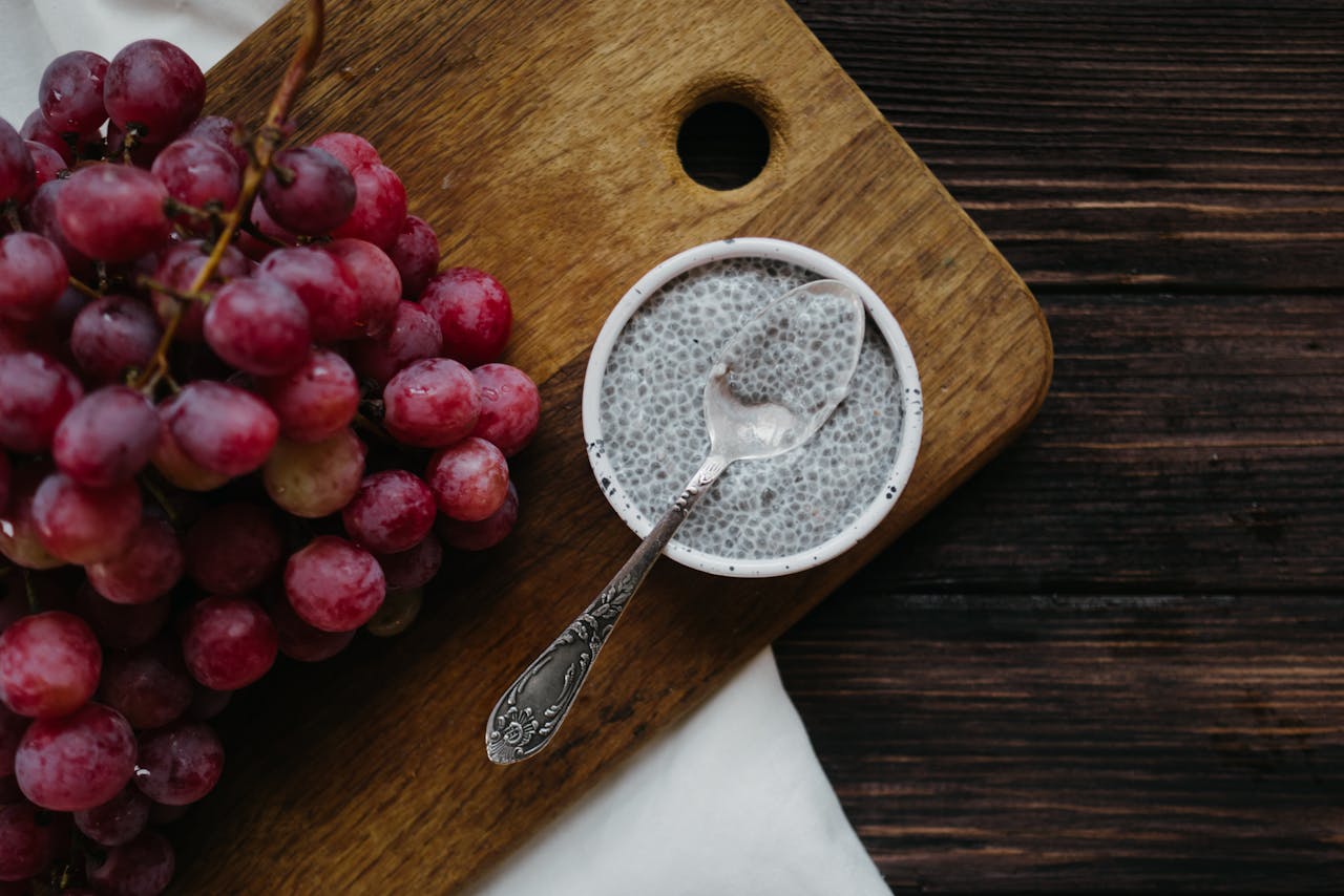 Healthy chia pudding with red grapes on rustic wooden background.