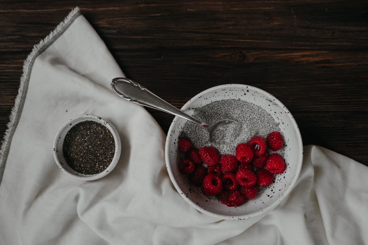 Delicious chia pudding topped with fresh raspberries and served with chia seeds on a rustic table setting.