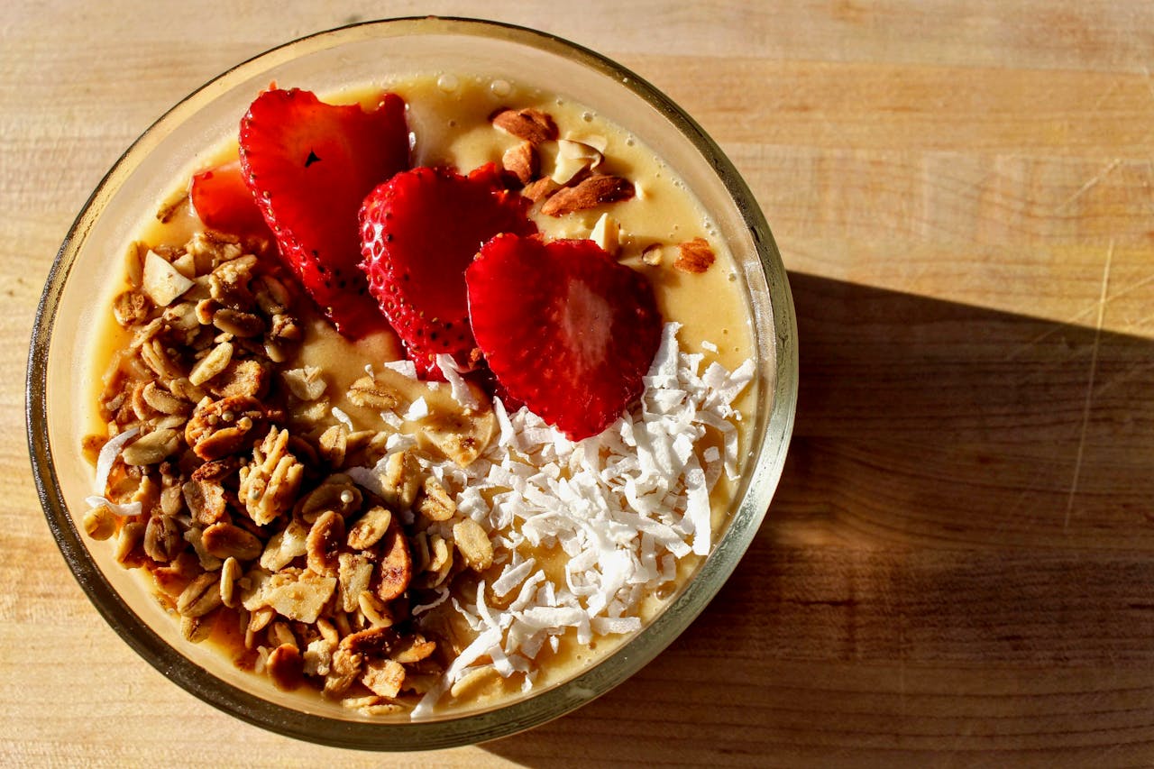 A close-up of a nutritious breakfast bowl with strawberries, granola, and coconut.